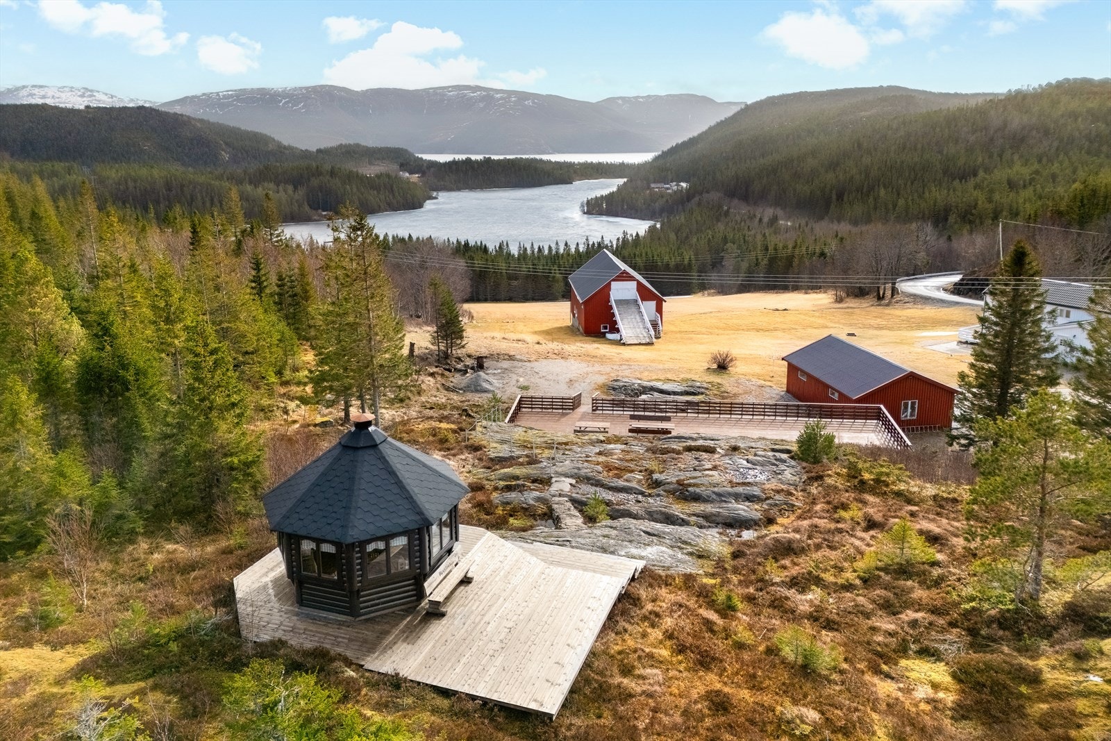 Eiendommen består av flere bygninger, bla grillhusmed platting rundt, platting, garasjer, låvebygning og bolighus Galleribilde