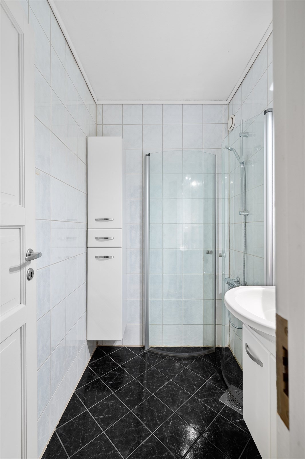 Badet er innredet med dusjhjørne m/glassdører, veggskap og servant med innredning, speil og belysning. Galleribilde