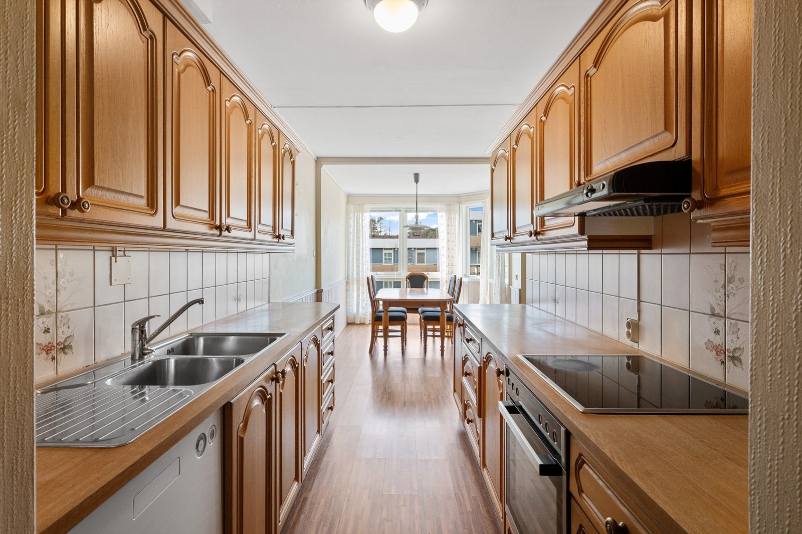 Kjøkkenet har innredning med laminert benkeplate, profilerte fronter og fliser mellom benkeplate og overskap. Galleribilde