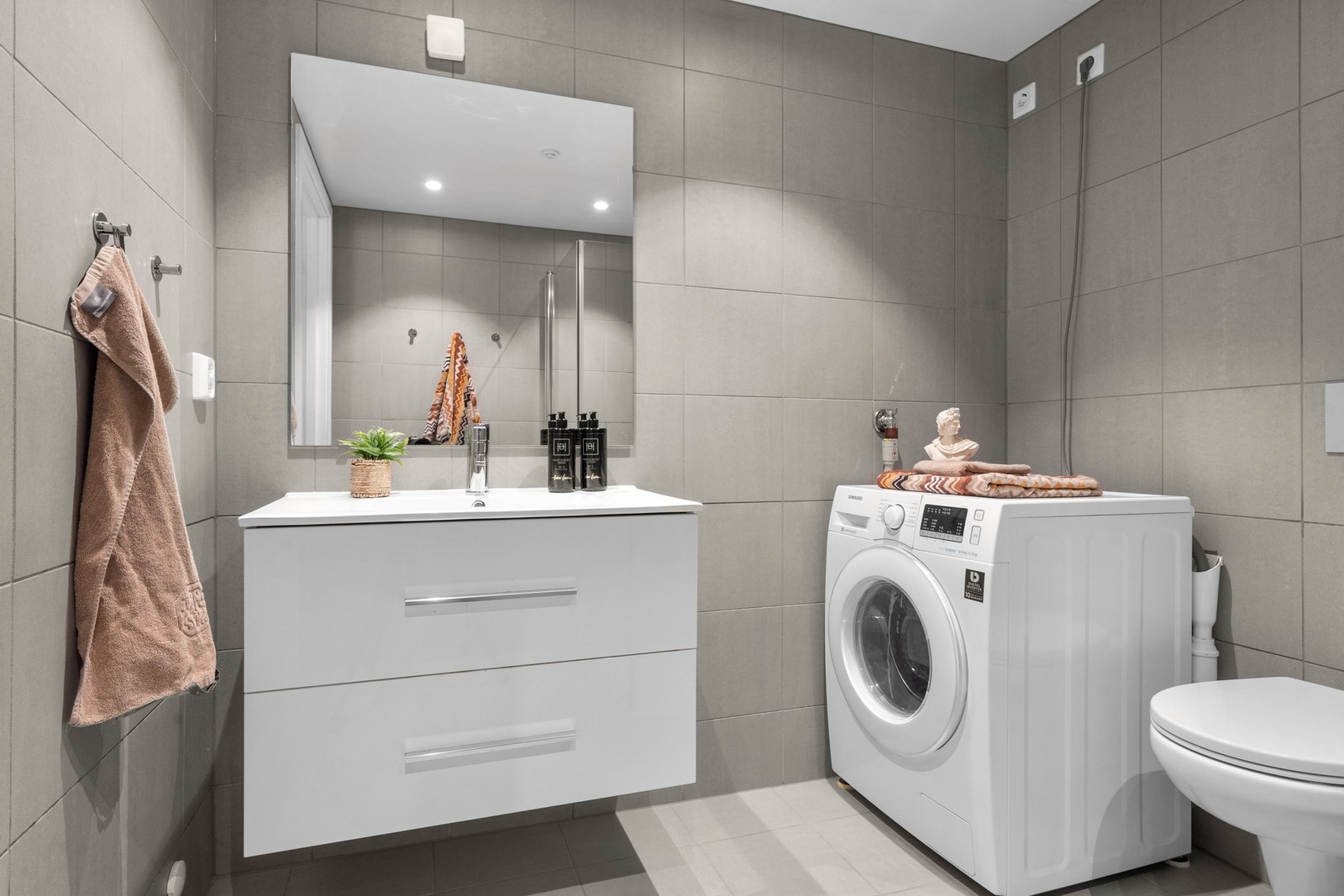 Rommet er utstyrt med varmekabler i gulvet og downlights i himlingen. Ellers består innredningen av en heldekkende servant på hvit skuffeseksjon med servantspeil, Galleribilde