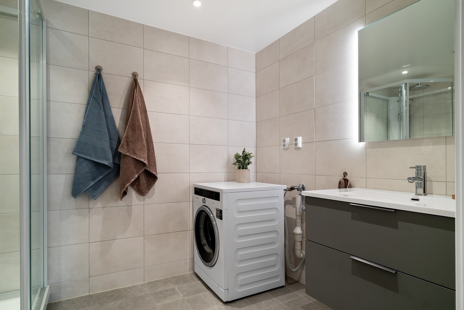 Lekkert, flislagt bad med opplegg for vaskemaskin og tørketrommel. Galleribilde