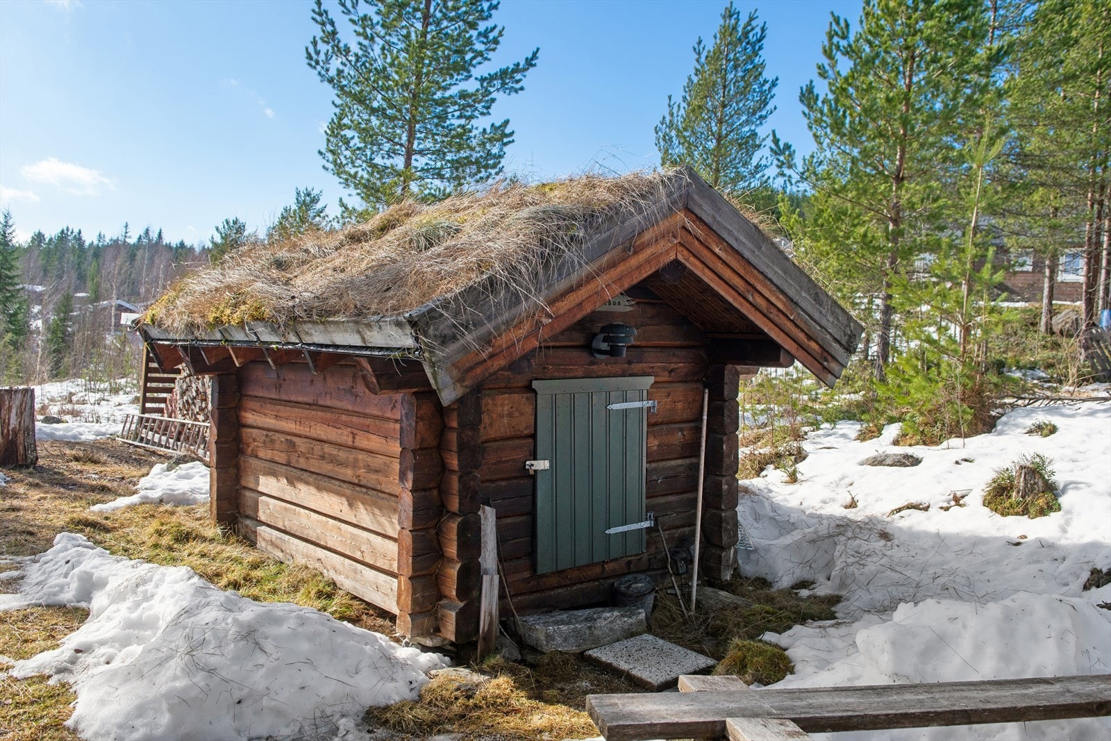 Et koselig håndlaftet uthus bidrar til å ramme inn tunet. Galleribilde