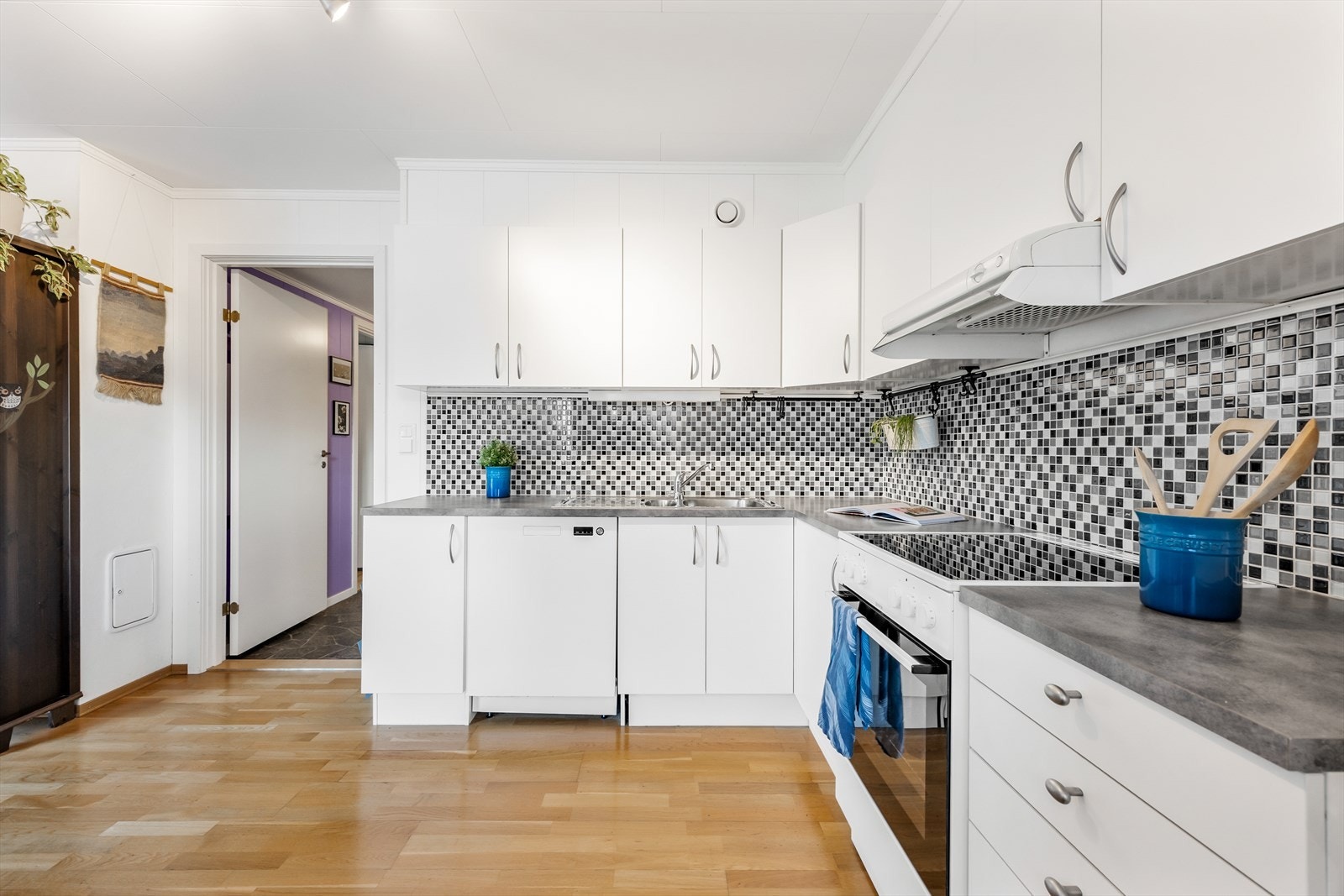 Det er fliser over benken og belysning under overskapene. Galleribilde