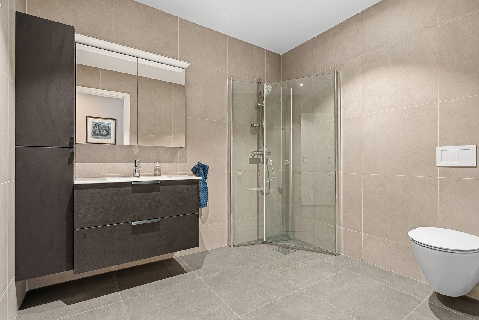 Baderom bestående av toalett, baderomsinnredning og dusjhjørne med innfellbare dusjdører. Galleribilde