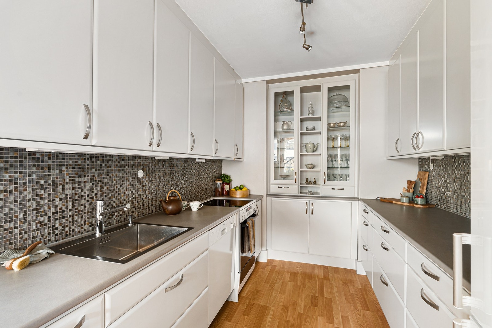 Kjøkkenet har en smart utforming med god arbeidsflate på begge sider, samt overskap helt opp til taket for maksimal plassutnyttelse. Galleribilde