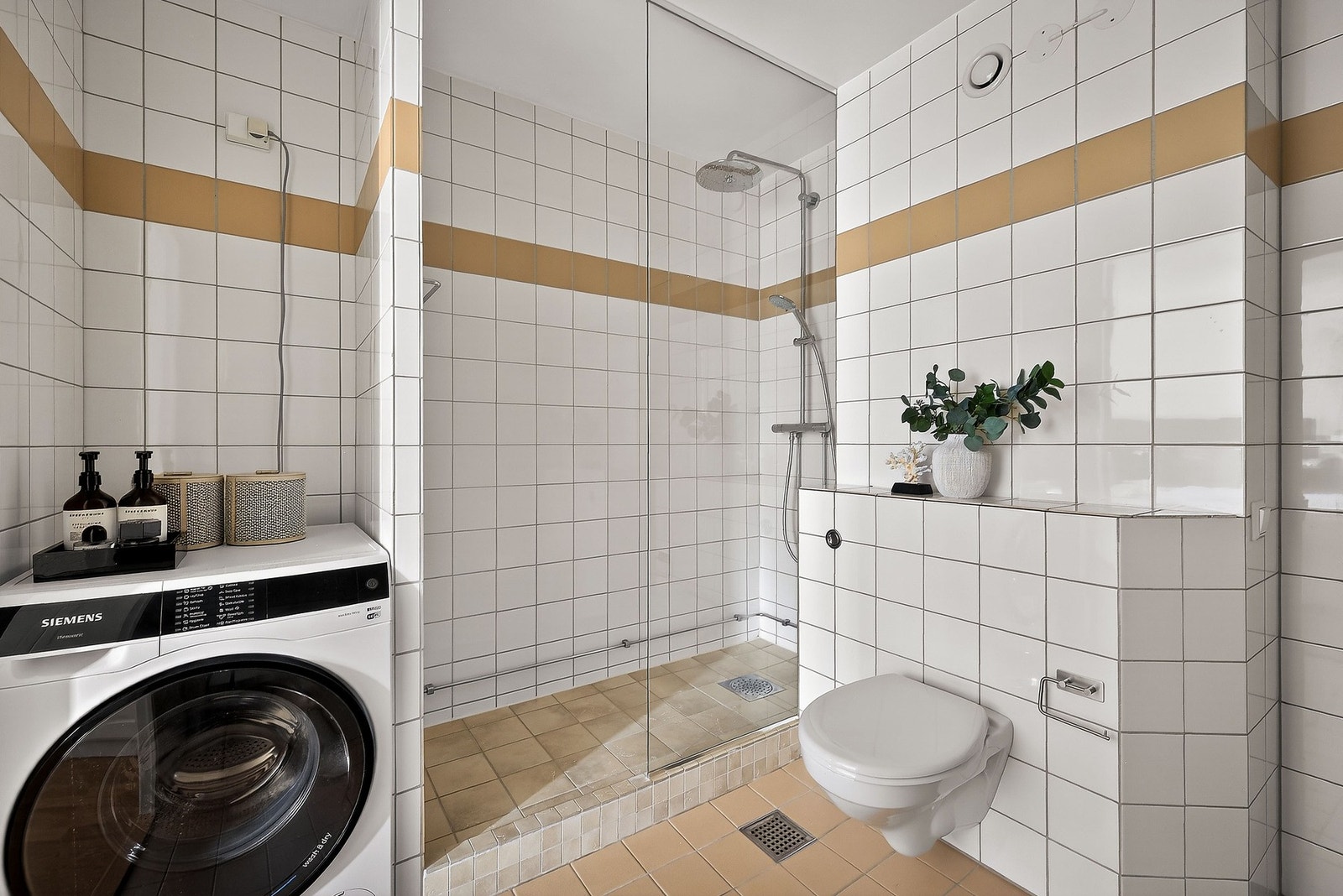 Videre er badet utstyrt med innredning med 2 nedfelte servanter, veggmontert toalett, dusjvegger/hjørne og opplegg for vaskemaskin. Galleribilde