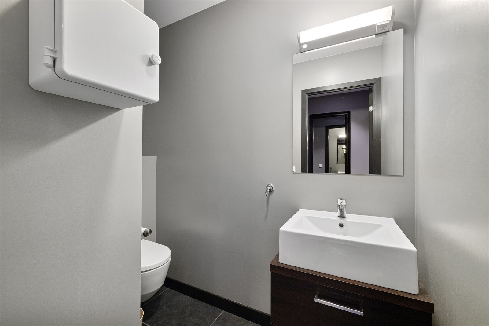 I leiligheten har du også et gjestetoalett. Innredet med vegghengt toalett og baderomsinnredning med servant Galleribilde