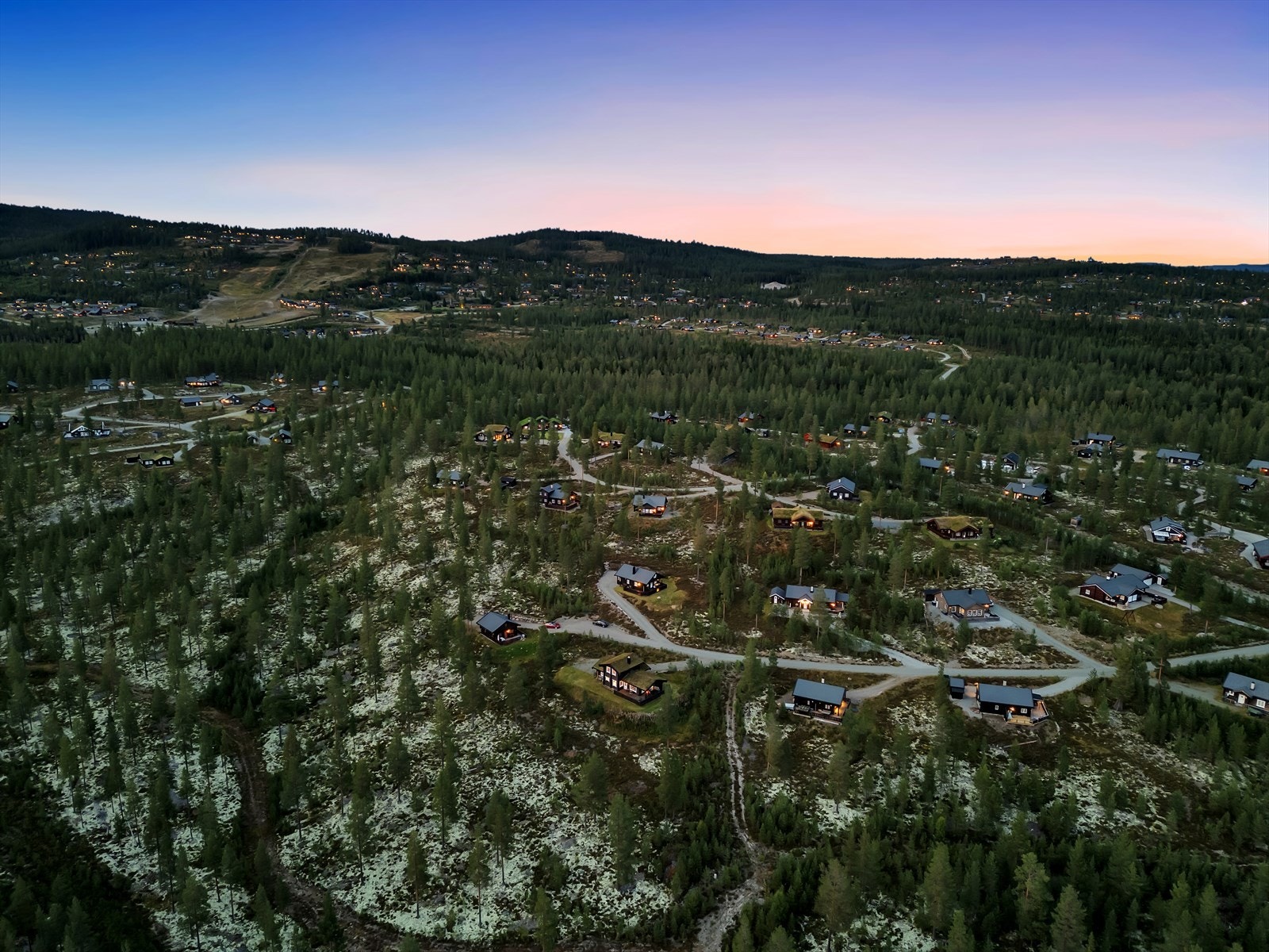 Hytteområdet er omgitt av skog og har flere fritidsboliger spredt utover det kuperte terrenget. Alpinbakken ses til venstre i bildet. Galleribilde