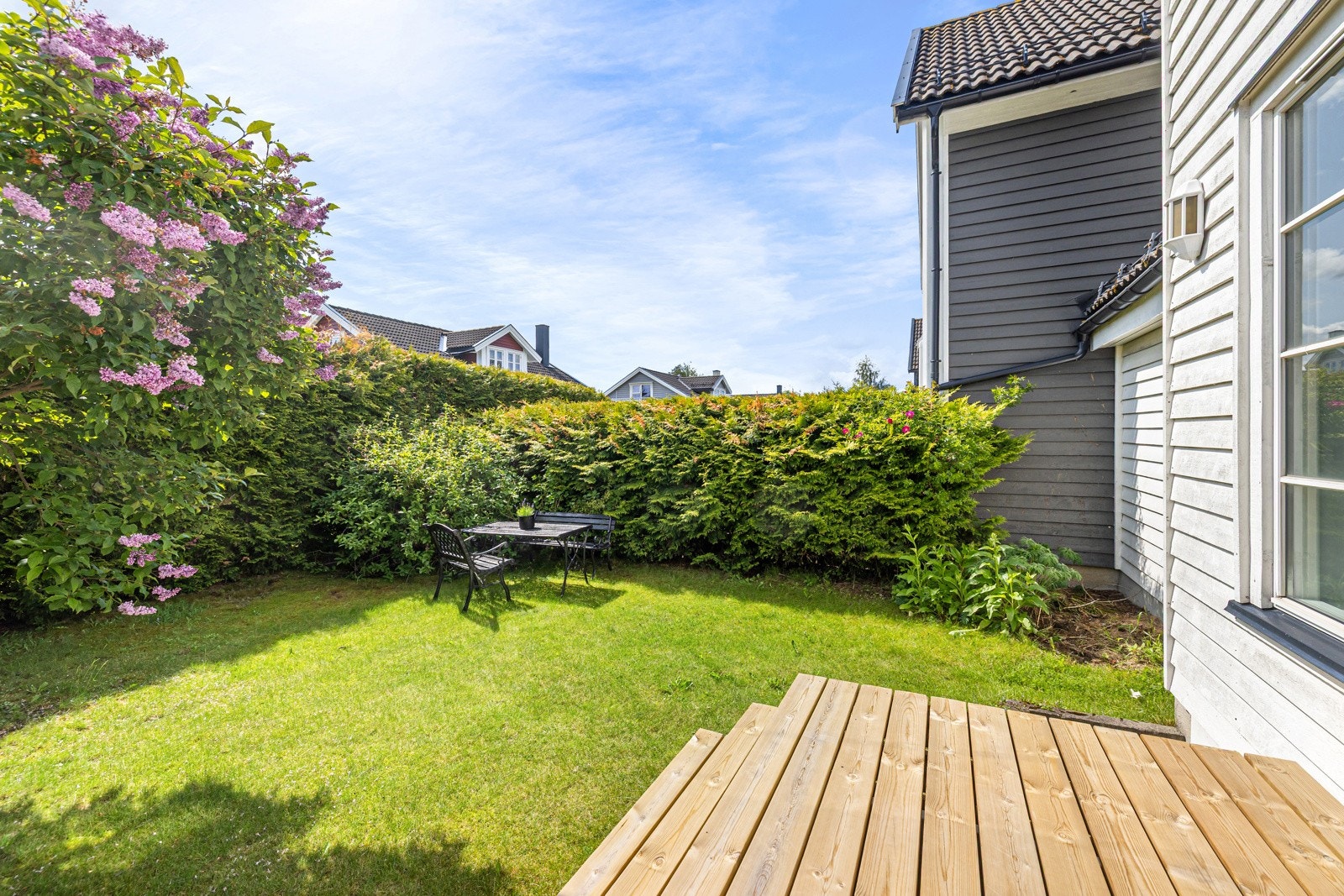 Boligen byr på en flott, skjermet hage omkranset av grønne trær og beplantning Galleribilde