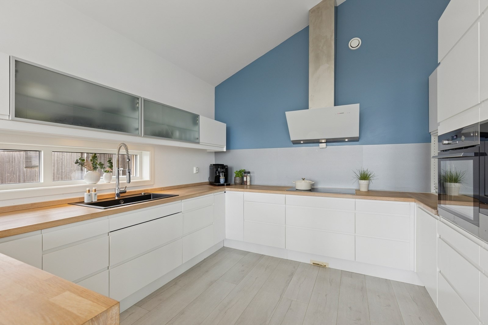 Moderne kjøkken i hvit utførelse. Det er godt med skap- og benkeplass. Galleribilde