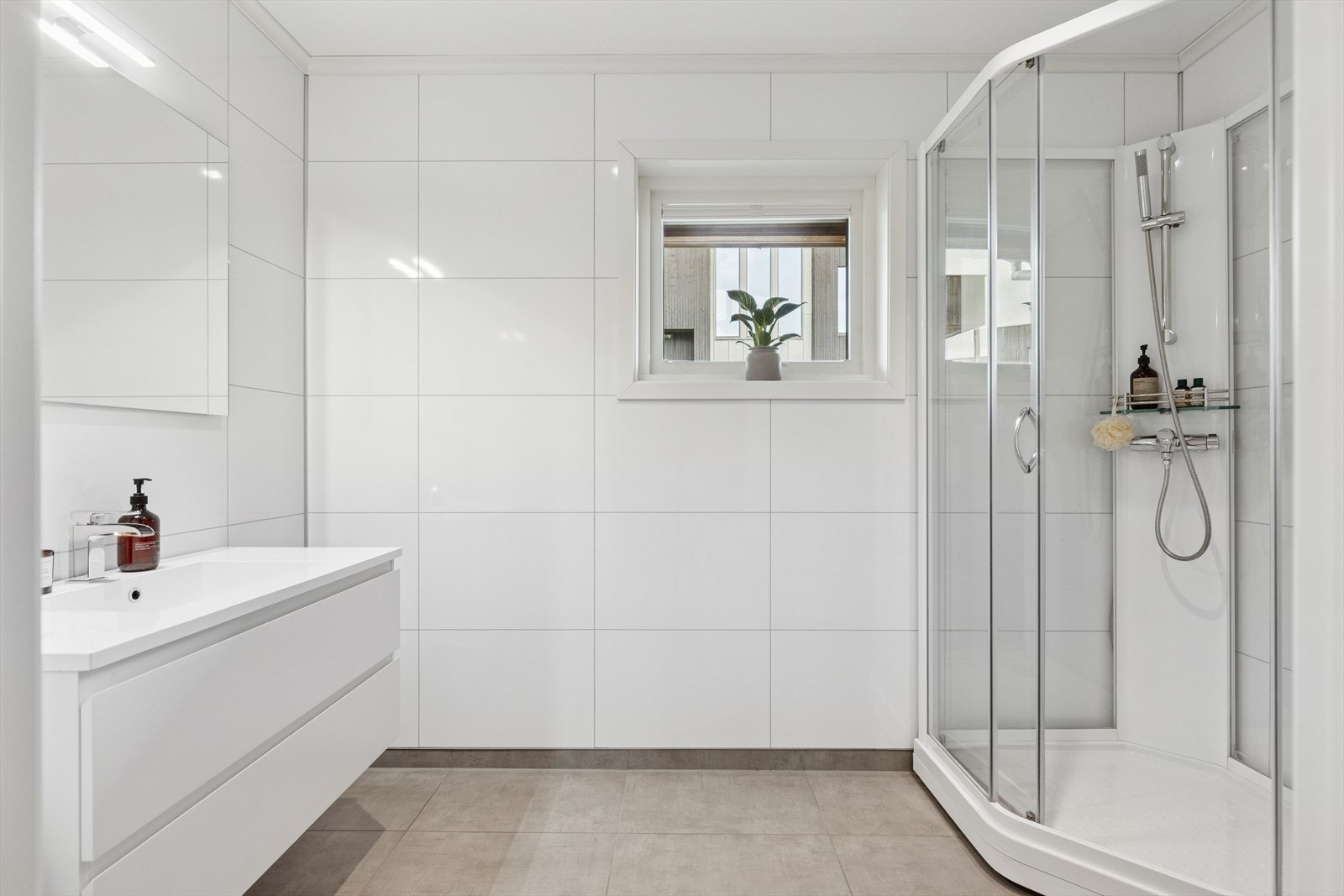 Baderom med dusjkabinett og servant med innredning, servant og belysning. Galleribilde