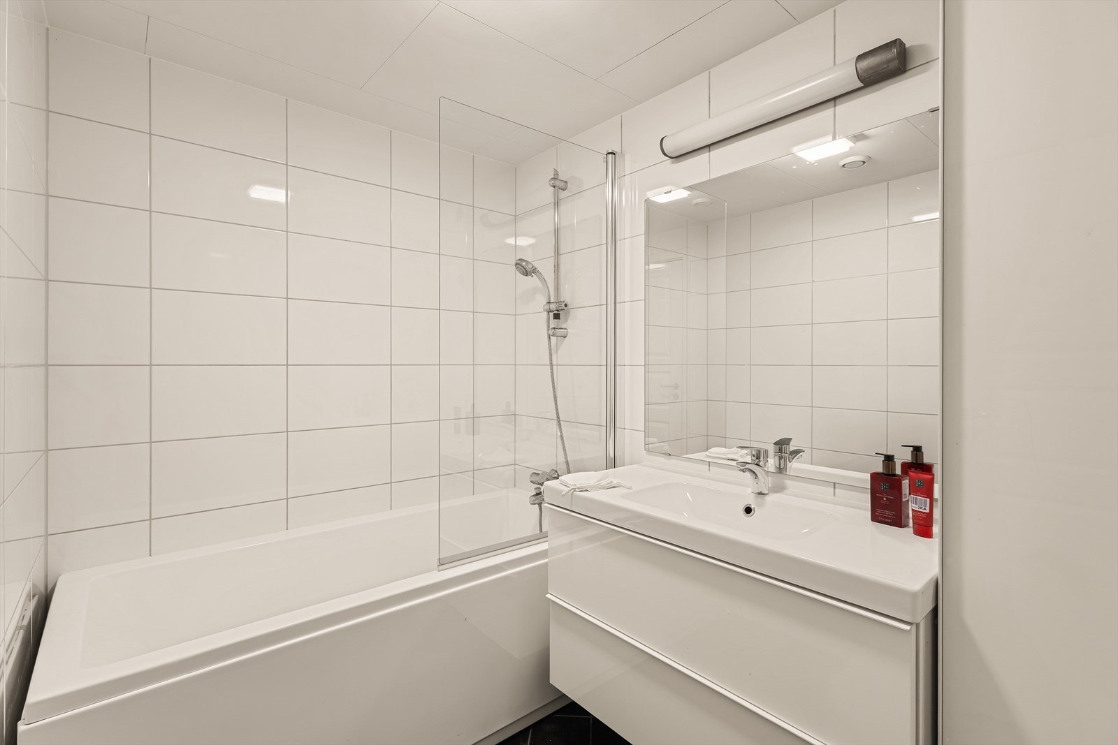 Baderommet er stort, moderne og velutstyrt med servant med møblement og speil, tilhørende belysning, samt dusjgarnityr og et praktisk badekar Galleribilde