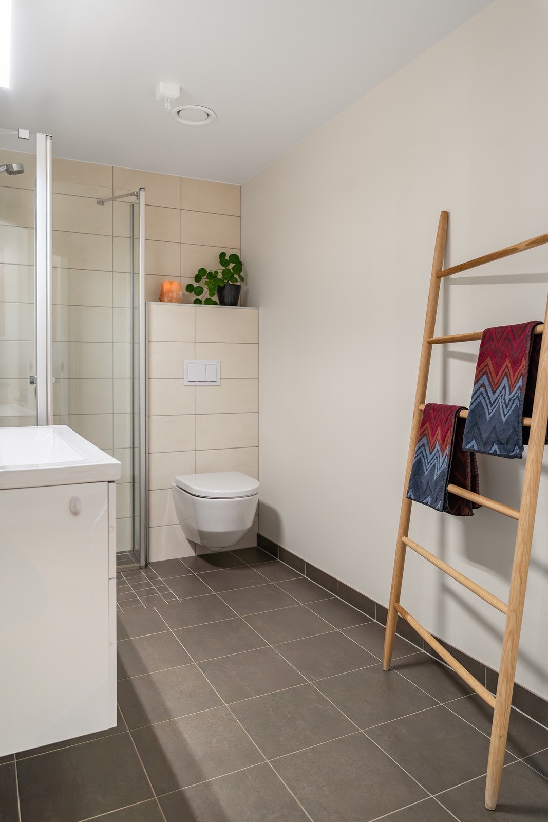 Det er vegghengt toalett, seksjon med servant og stedsbygd dusjhjørne. Galleribilde