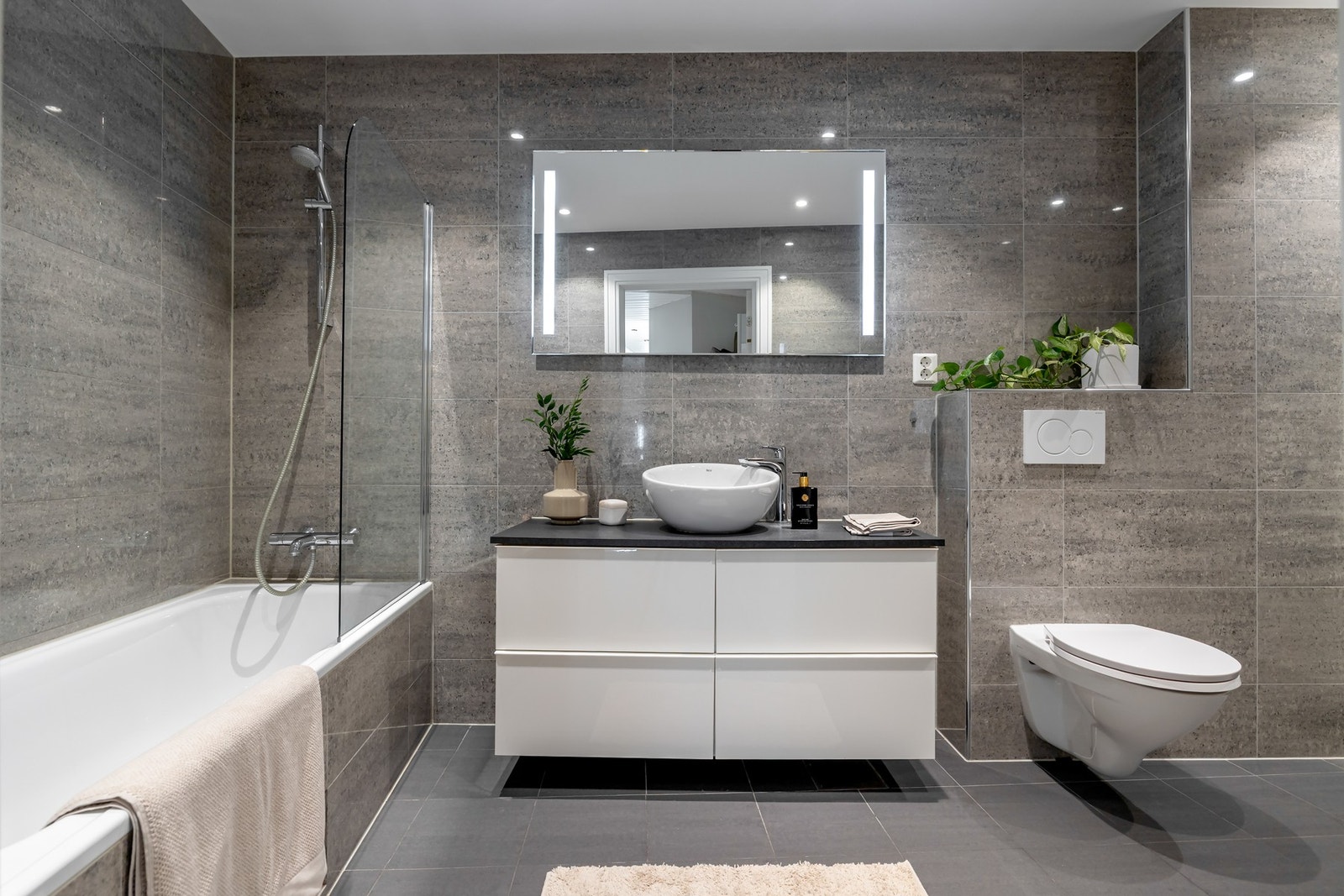 Badet er innredet med badekar med dusjløsning, vegghengt toalett og en romslig servantinnredning med gode oppbevaringsmuligheter. Galleribilde