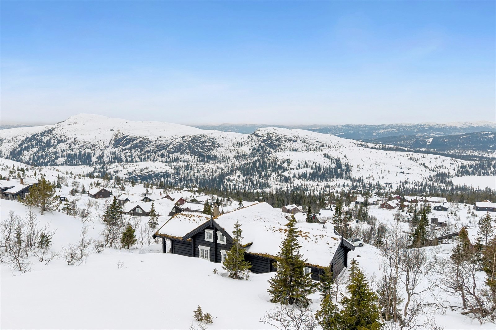 Hytta ligger flott til i et hellende terreng, med en vidstrakt utsikt over fjellandskapet. Galleribilde