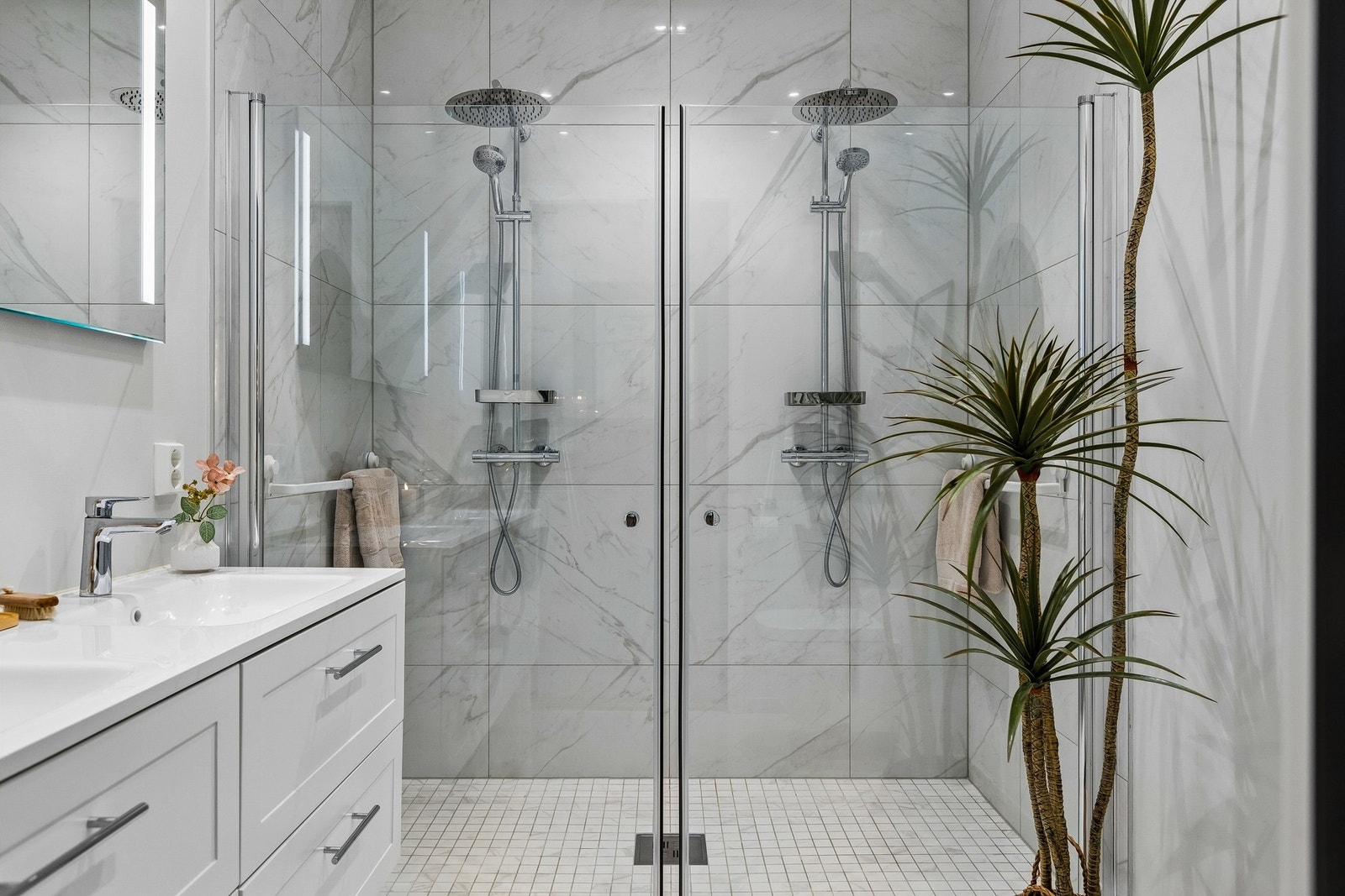 Badet i hovedetasjen oppleves elegant med flislagte flater og dobbel dusj. Galleribilde