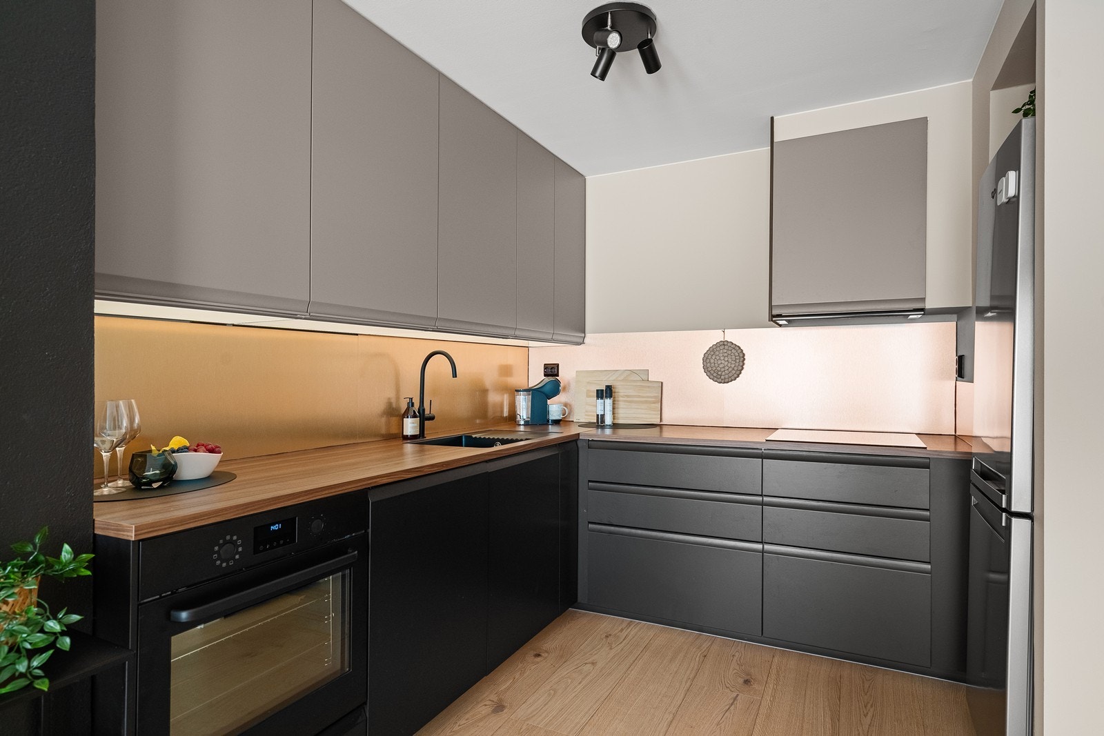 Integrerte sorte elementer som stekeovn, vask, armatur og koketopp skaper en gjennomført stil. Galleribilde