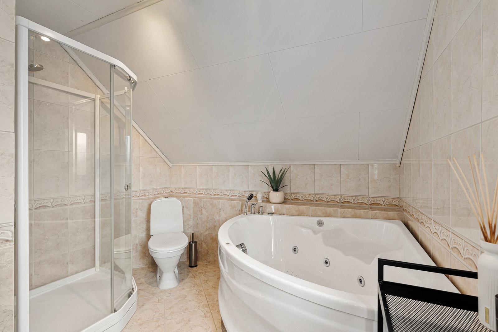 Flislagt baderom med toalett, dusjkabinett og badekar. Galleribilde