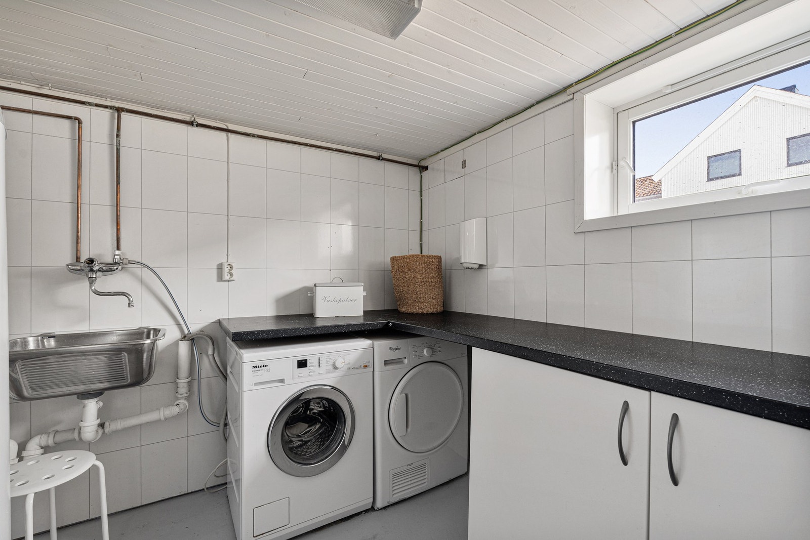 Praktisk vaskerom med kjøkkeninnredning, utslagsvask og oppleggg til vaskemaskin. Galleribilde