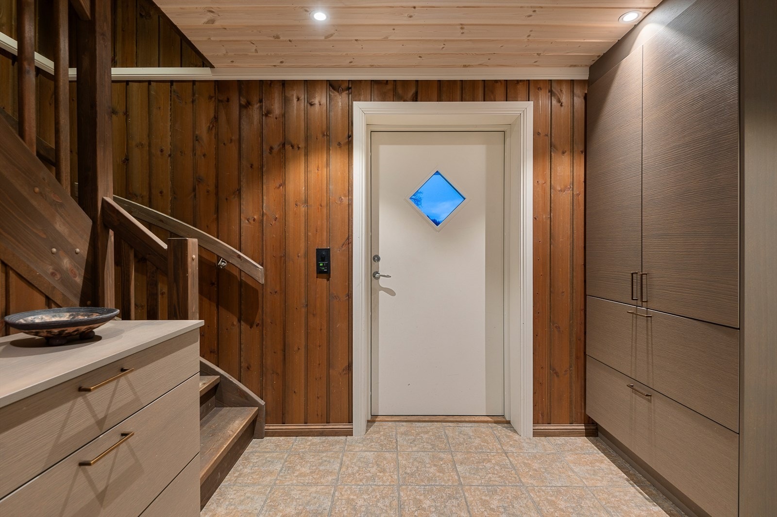 Romslig entre/gang med flislagt gulv med varme og downlights i himling. God plass til å henge fra seg alt av yttertøy i garderobeskap og kommode levert av Fossline Galleribilde