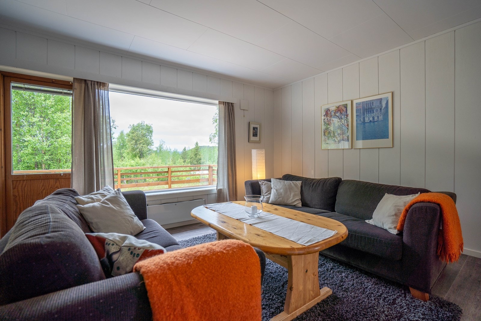 Lys og innbydende stue med store vinduer som gir behagelig utsikt til frodig natur og terrasse. Galleribilde