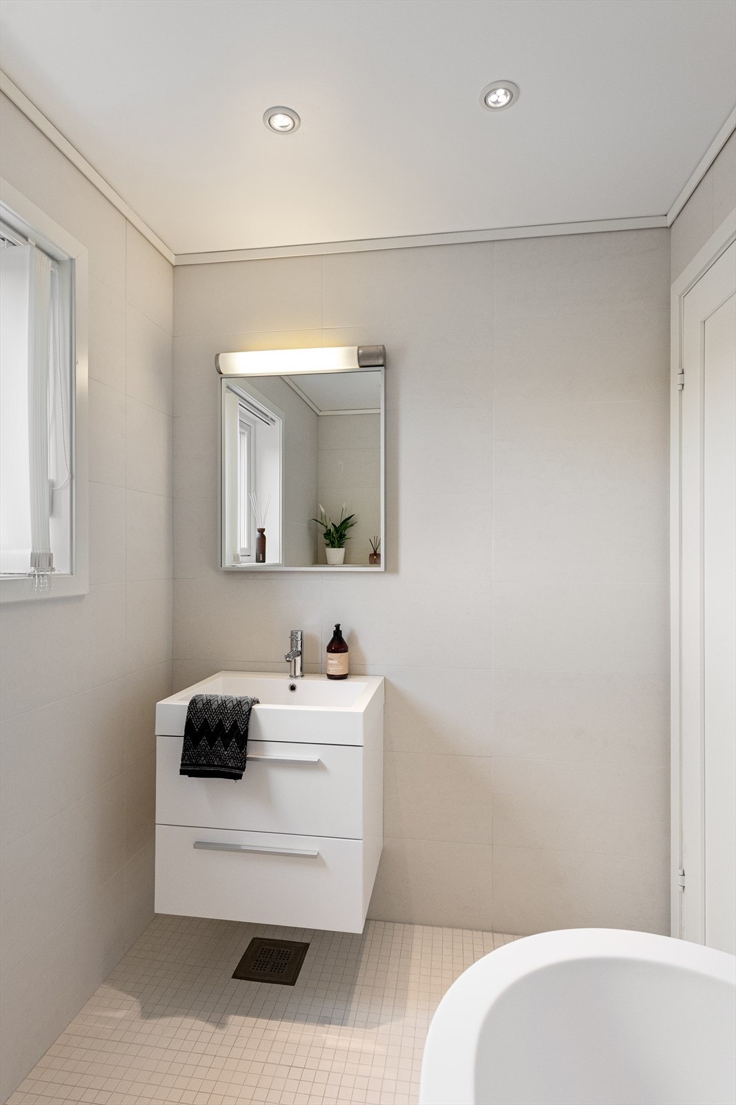 Servantinnredningen har en elegant, ovenpåliggende servant og speil med integrert belysning Galleribilde