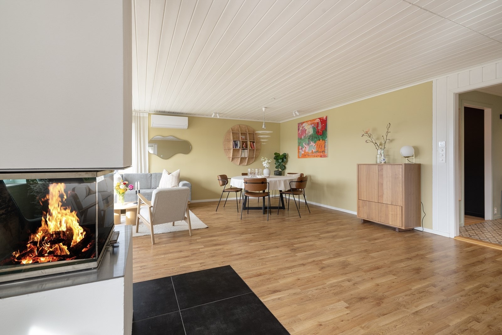 Overflatene består av laminat på gulv, malte vegger og malt panel i tak. Ved ildstedet er det flislagt gulv, og det er også innslag av malt panel på vegg mot entré. Galleribilde