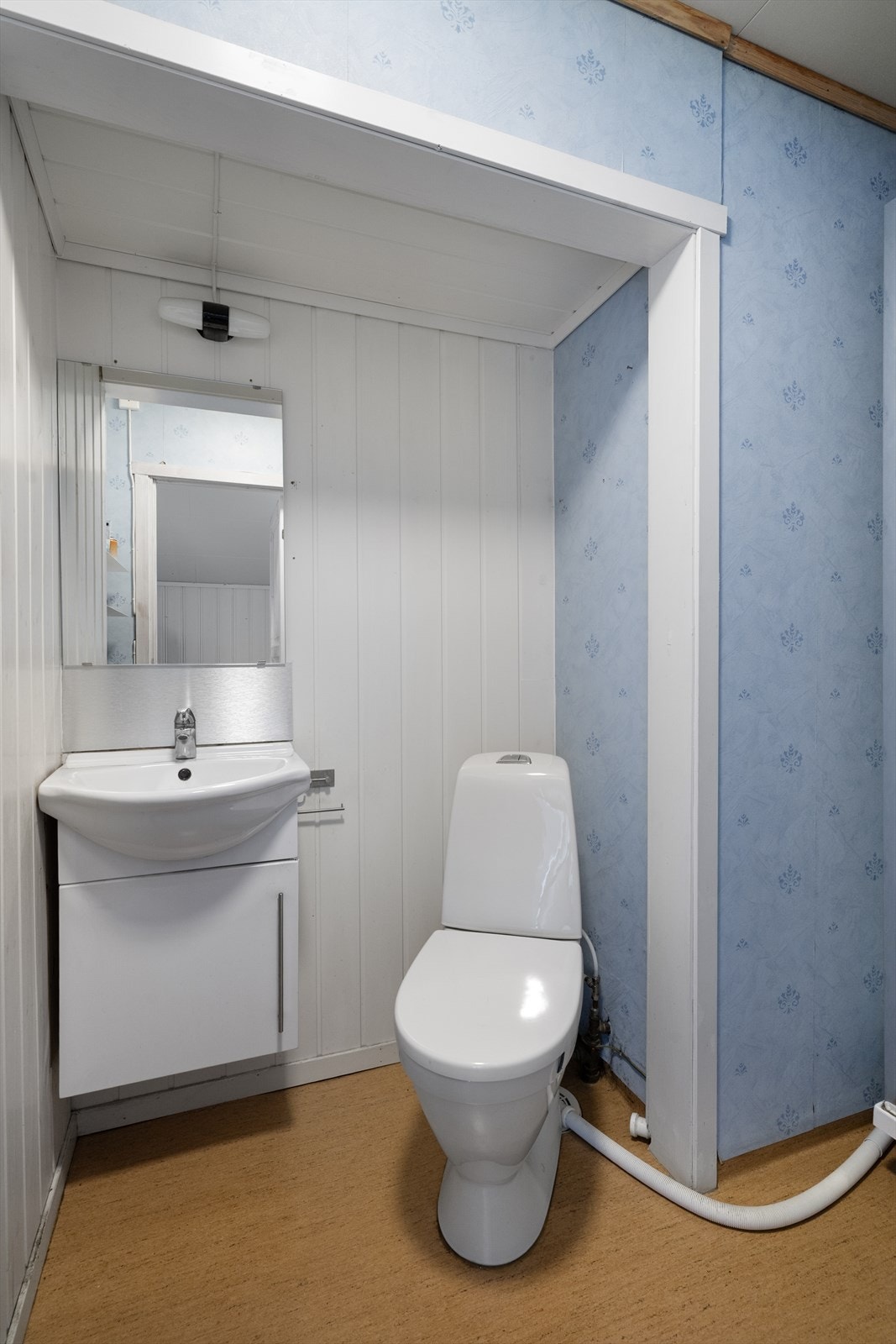 Badet er av eldre standard og er utstyrt med dusjkabinett, samt nyere gulvmontert toalett og servantskap med heldekkende servant. Galleribilde