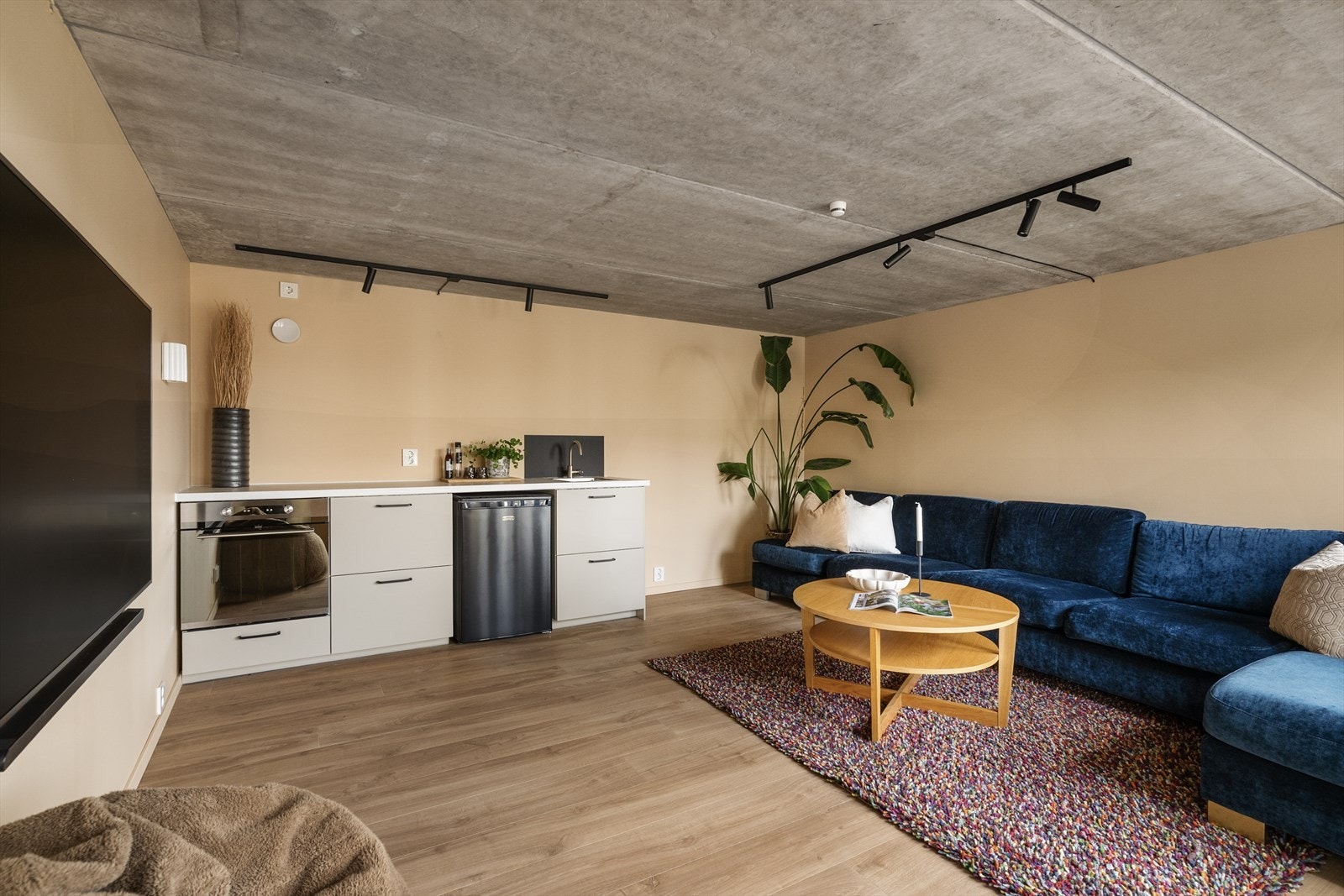 Stilig kjellerstue i underetasjen, med pene overflater og kjøkkeninnredning med integrert stekeovn, nedfelt kum og avsatt plass til kjøleskap under benk. Galleribilde