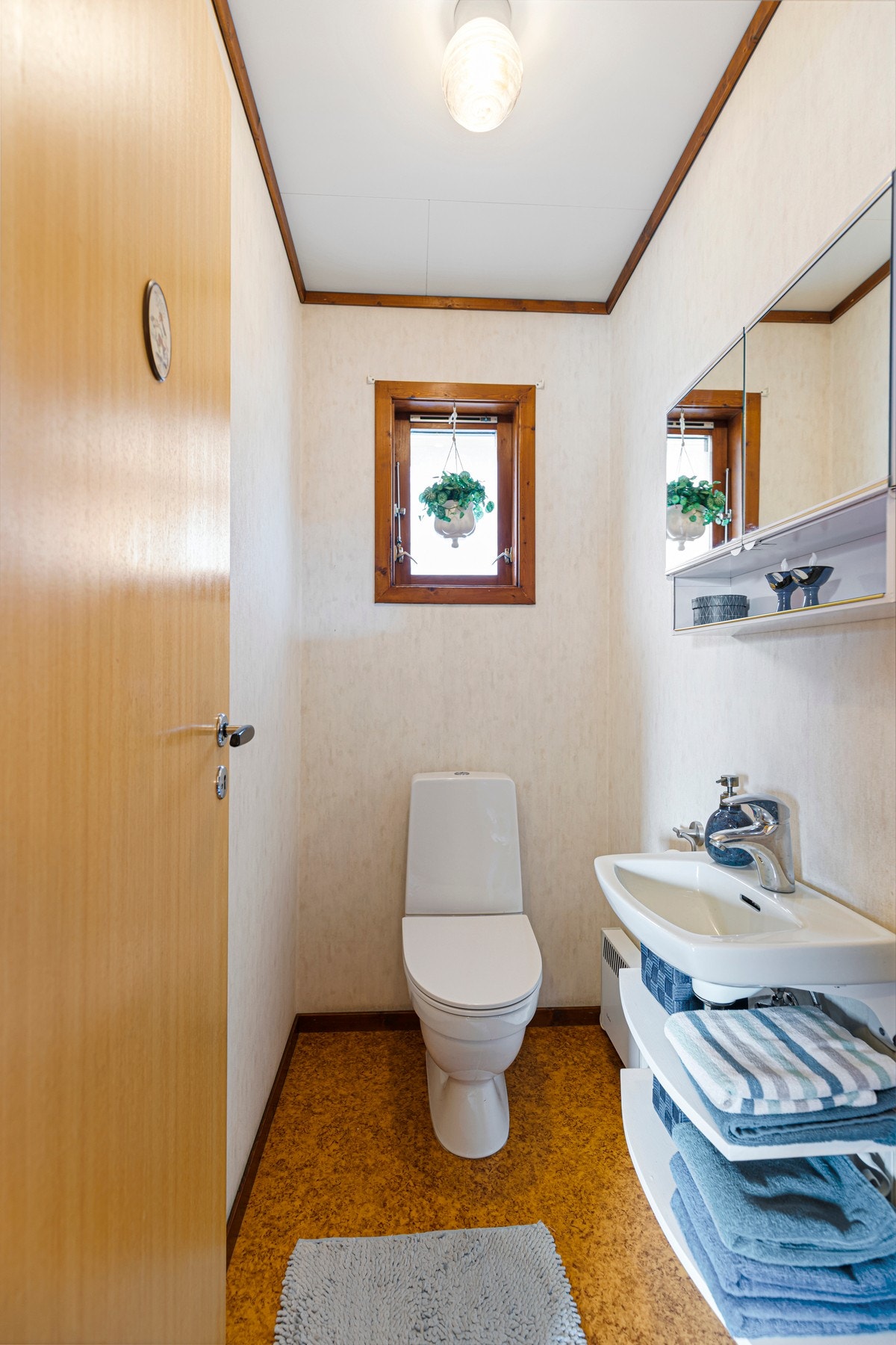 Toalettrom med laminat på gulv og malte flater på veggene. Rommet er utstyrt med wc og vegghengt servant. Galleribilde