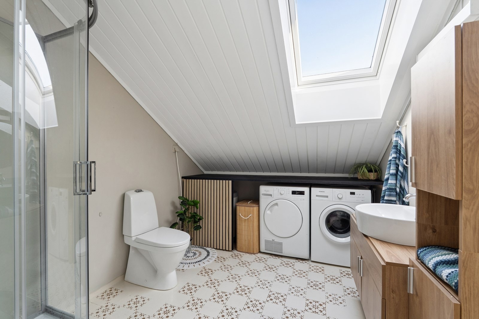 Badet på 5,3 m² har vinylbelegg på gulv, våtromstapet på veggene og et takvindu som gir godt med dagslys. Galleribilde