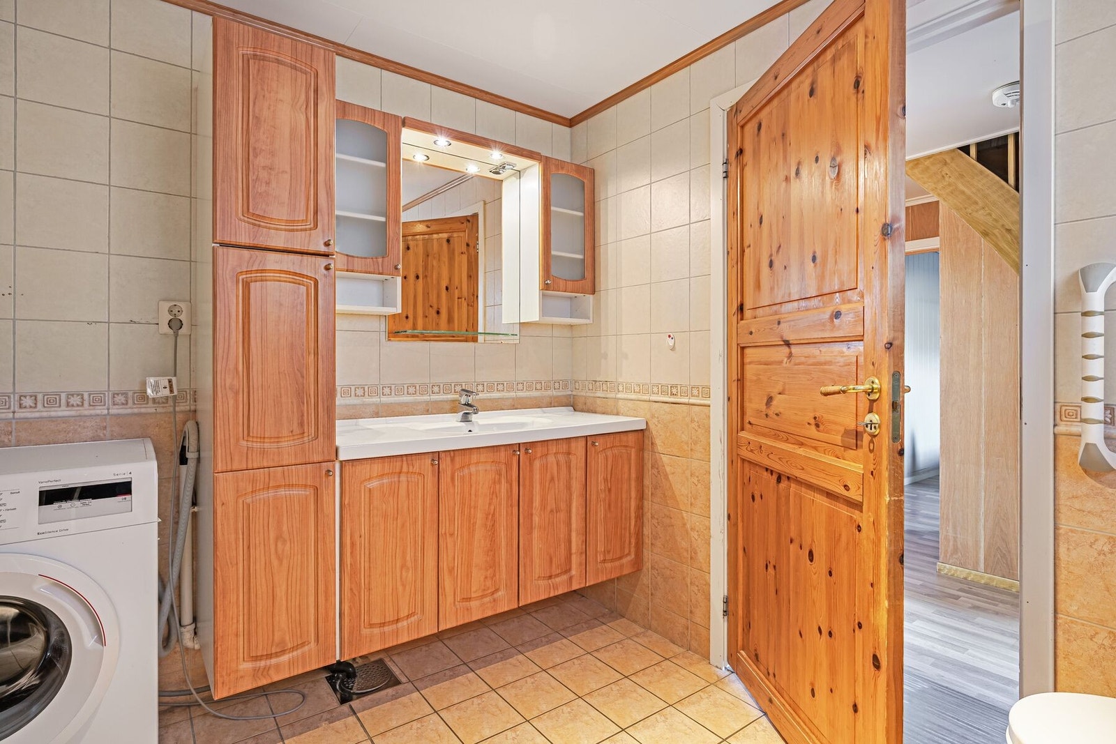 Badet er utstyrt med servant i innredning, dusjplass, toalett og opplegg for vaskemaskin Galleribilde