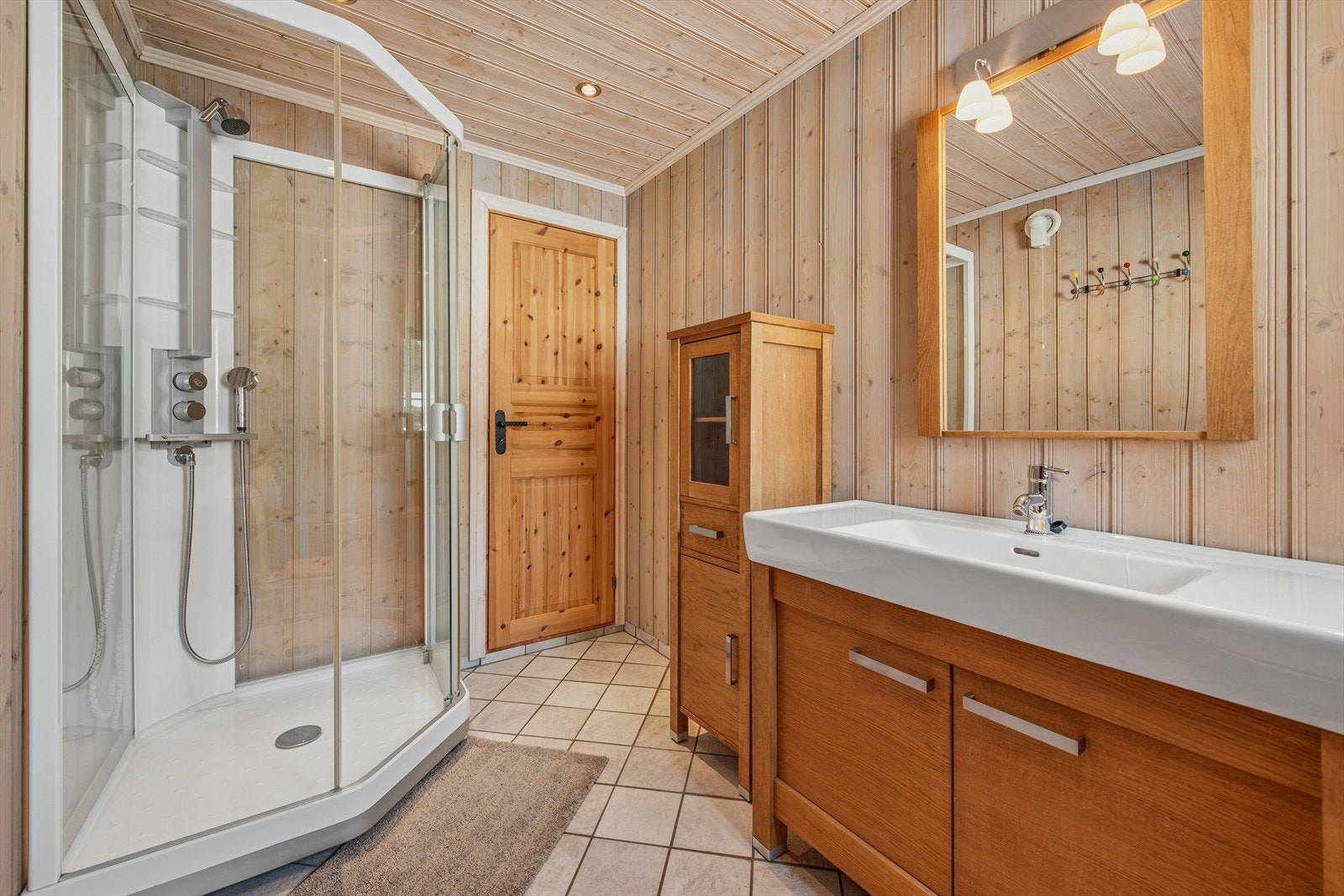 Badet er fra 2006. Flislagt gulv med elektriske varmekabler, mens veggene og taket har panel. Downlights i himlingen. Galleribilde