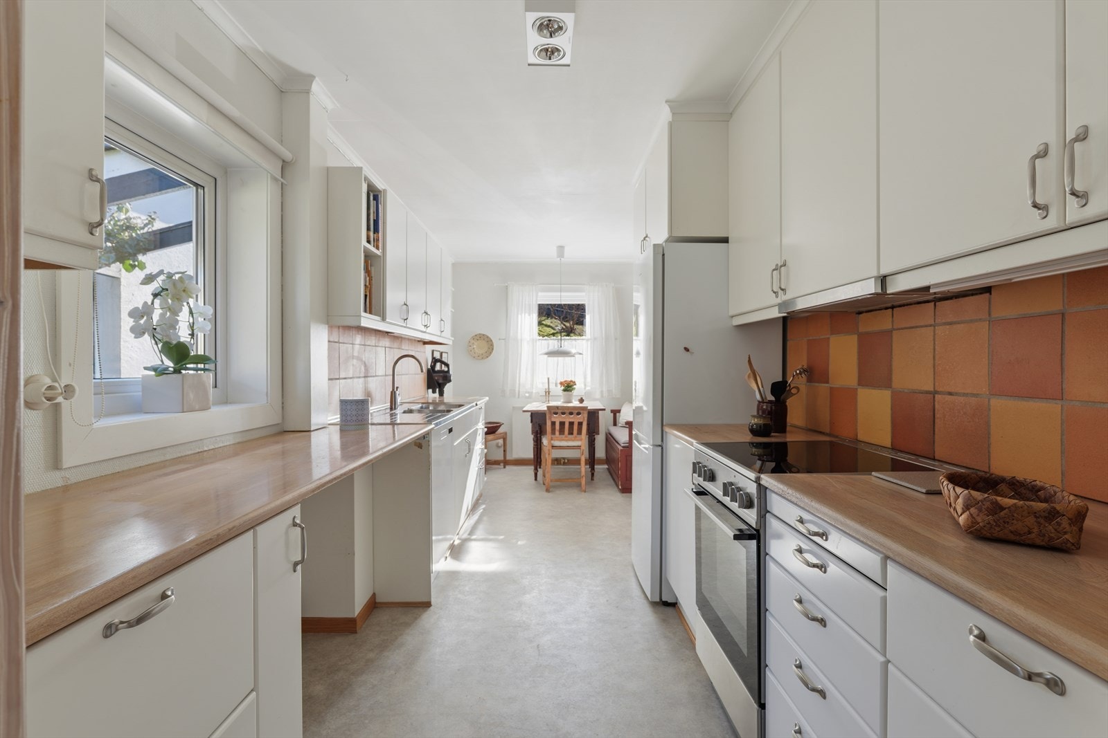 Kjøkkenet har en langstrakt utforming som er typisk for arkitekturen på denne boligen - noe som gir godt med skap- og benkeplass Galleribilde