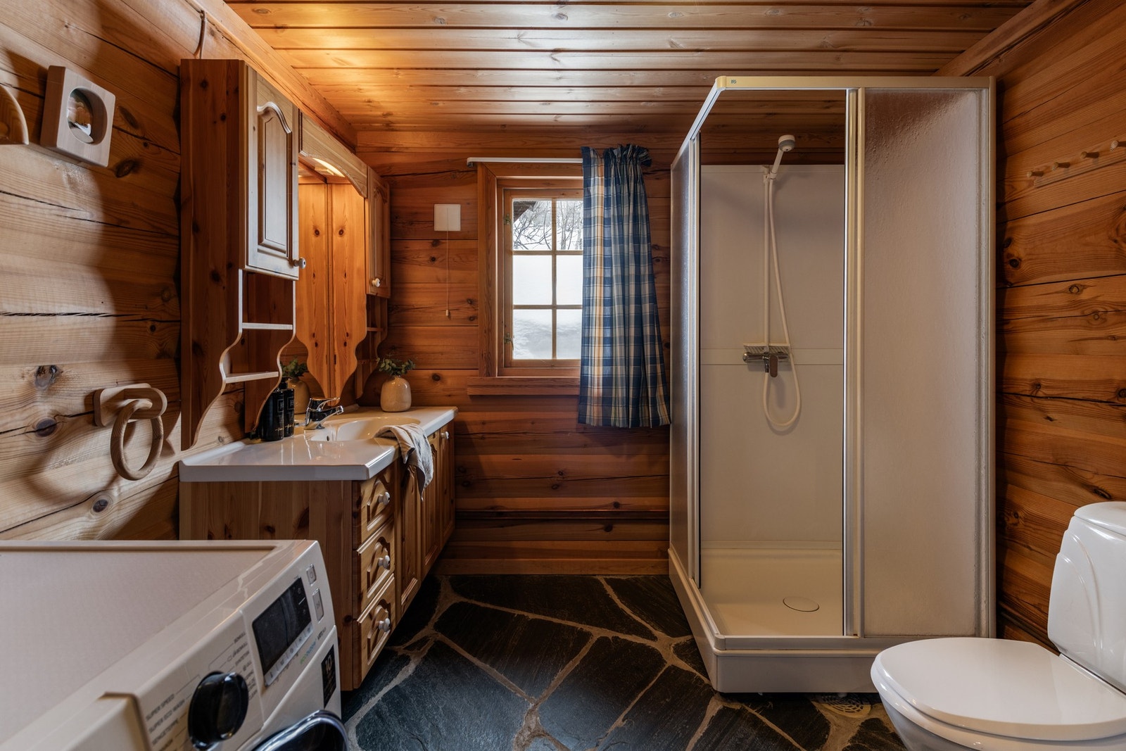 Badet har skifer på gulv og maskinlaft på vegger Galleribilde