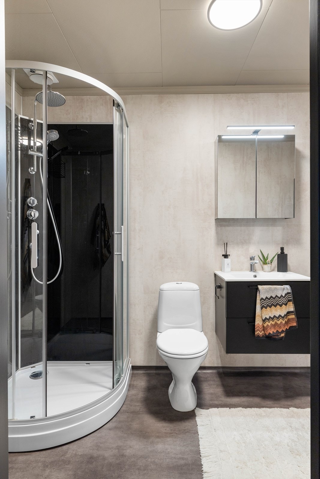 Det er utstyrt med baderomsplater på vegger, belegg på gulv, dusjkabinett, en moderne baderomsinnredning og opplegg for vaskemaskin. Galleribilde