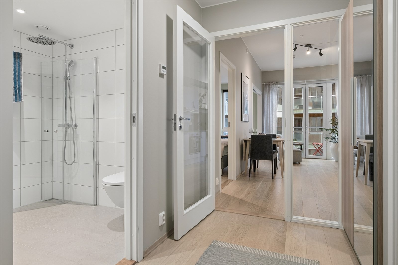 Fra gangen åpner leiligheten seg opp mot oppholdsrommene, med badet praktisk plassert rett ved inngangen. Galleribilde