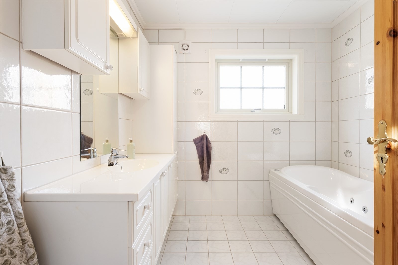 Badet i 1.etasje har flis på veggar og golv. Her har du vegghengt toalett, badekar, servantskap og dusjnisje med glasdørar. Galleribilde