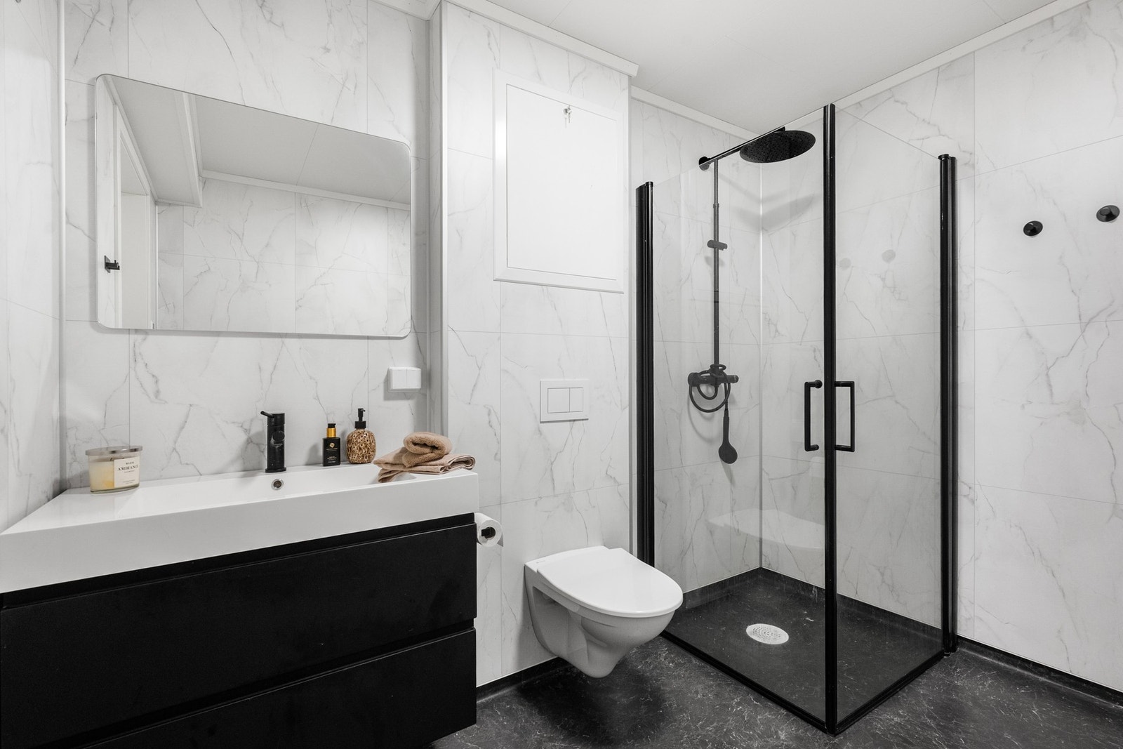 Bad/wc med dusjhjørne, vegghengt toalett og servant med oppbevaringsskuffer. Galleribilde