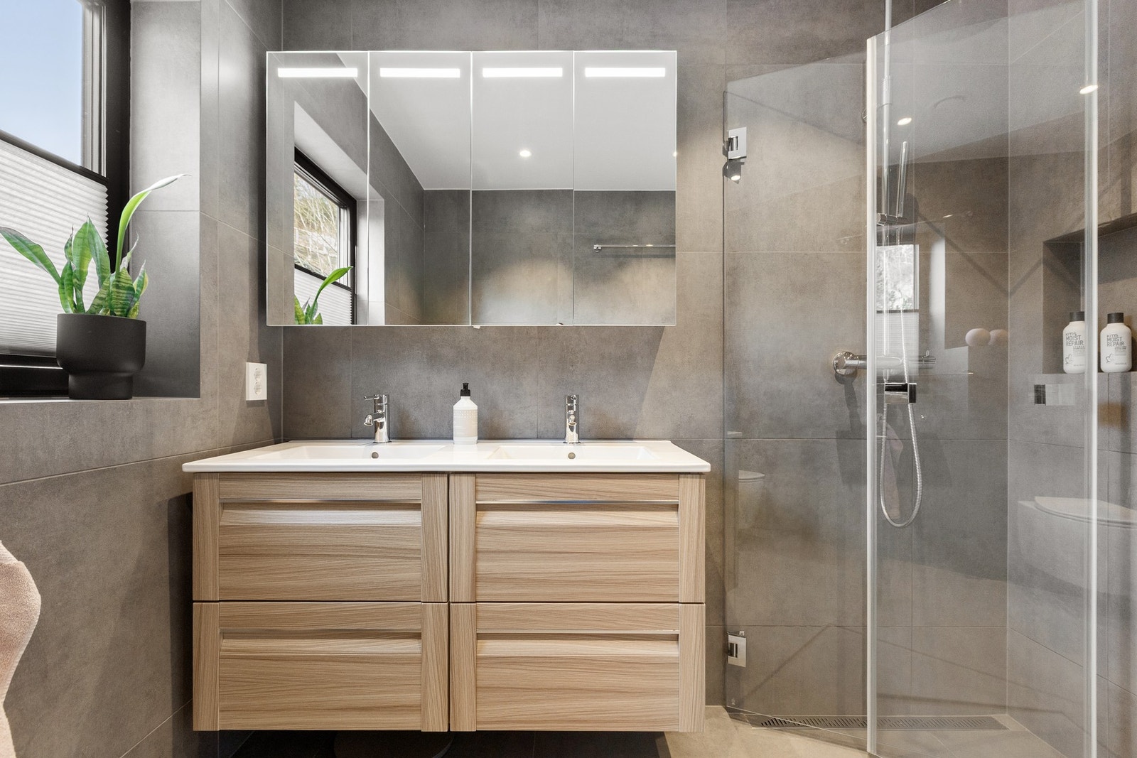 Badet er innredet med vegghengt toalett,
servantskap med heldekkende dobbel porselenservant, dobbelt speilskap med lys og regnfallsdusj. Galleribilde