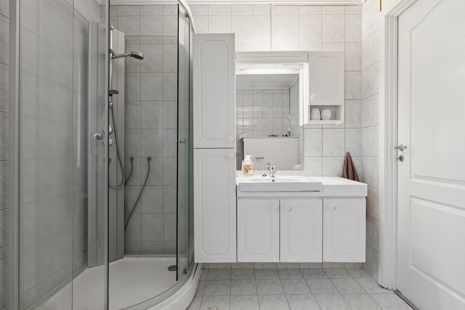 Baderommet er innredet med dusjkabinett, toalett, servant med underskap, speil med belysning samt et høyskap som gir ekstra oppbevaringsplass. Galleribilde