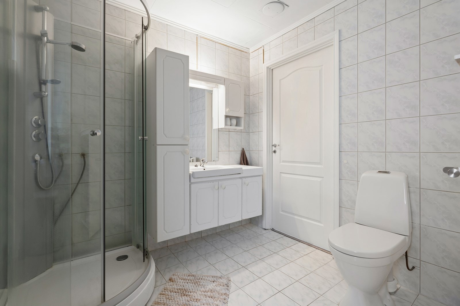 Tidløst baderom med flislagte gulv og vegger. Elektriske varmekabler i gulvet sørger for behagelig varme og økt komfort i hverdagen Galleribilde