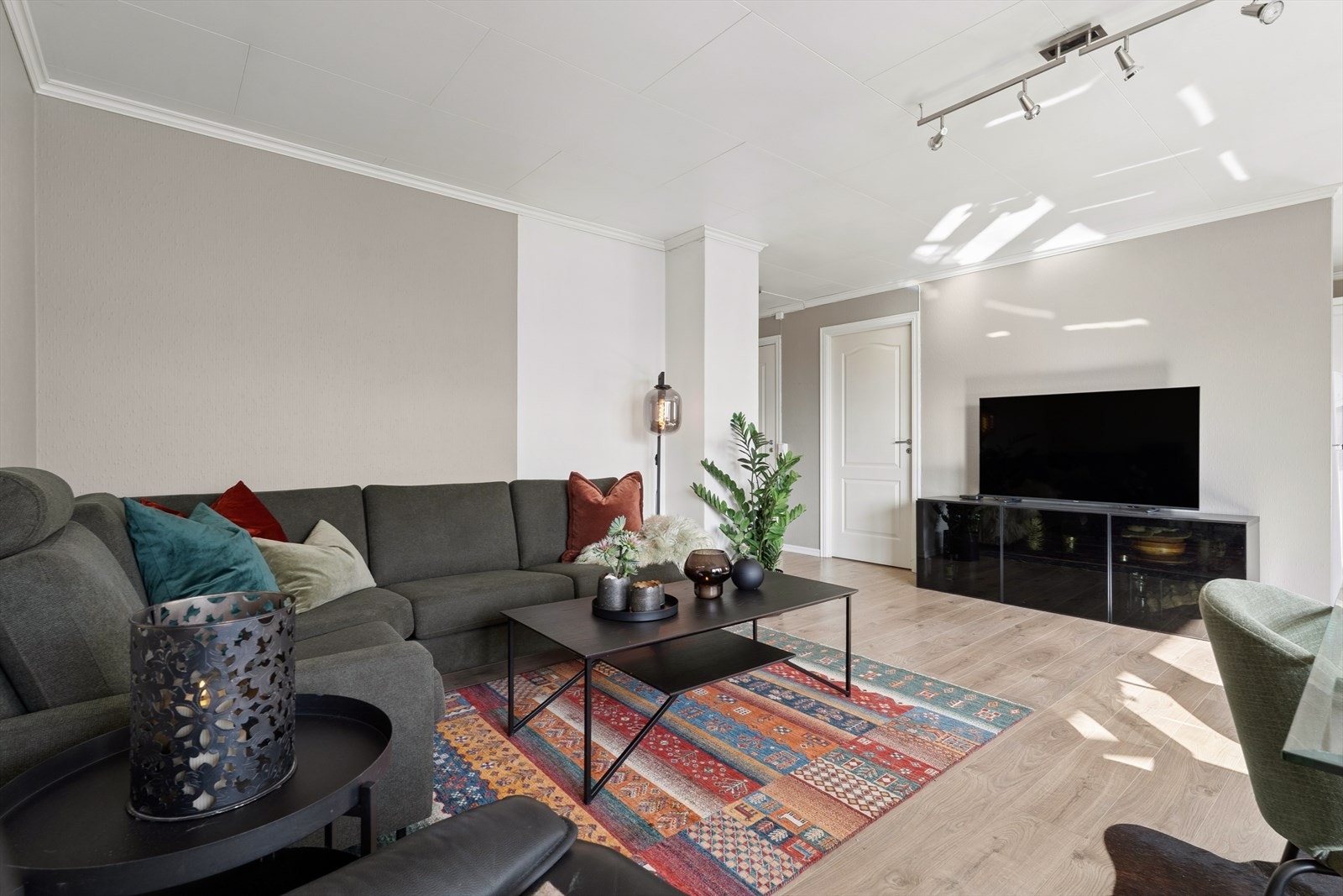 Rommet har en praktisk utforming som gir en naturlig flyt videre til øvrige oppholdsrom, noe som gjør helheten både funksjonell og sosialt inviterende Galleribilde