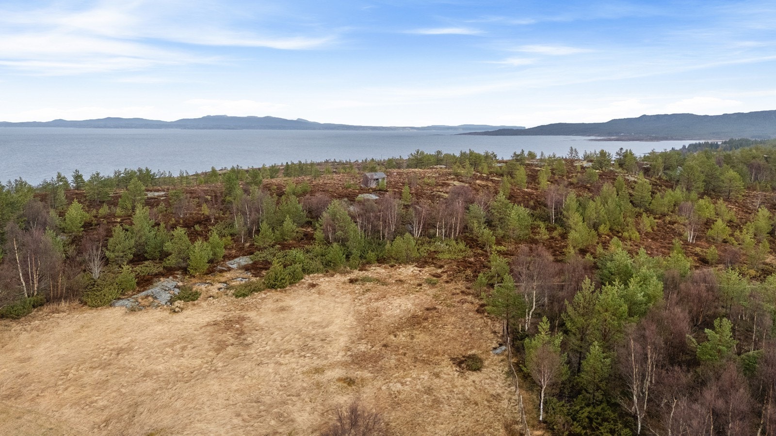 Eiendomsgrensene går litt forbi et gammelt uthus som står på eiendommen. I bakgrunnen ser man mot Hitra og Smøla. Galleribilde