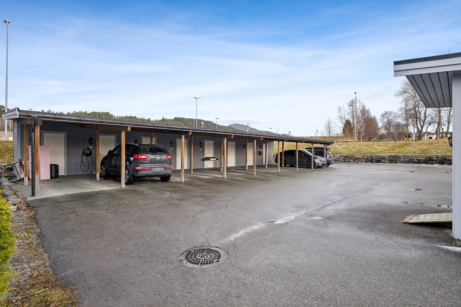 Foran carporten er det asfaltert parkeringsareal som sikrer enkel adkomst og god plass til biloppstilling. Det er både tilgang til strøm og muligheter for å montere elbillader, noe som gjør parkeringsløsningen fremtidsrettet og svært praktisk. Galleribilde