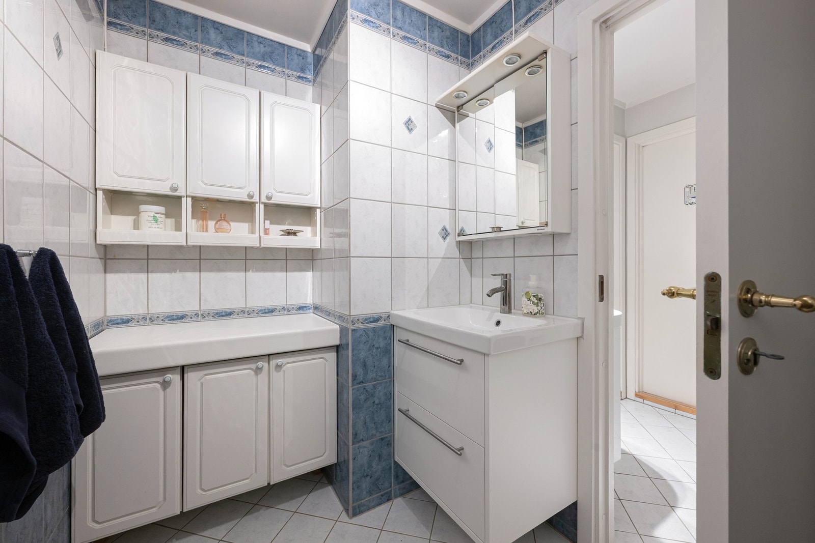 Badet har en funksjonell løsning med dusjkabinett og servant med skap, som gir nyttig oppbevaringsplass. Galleribilde