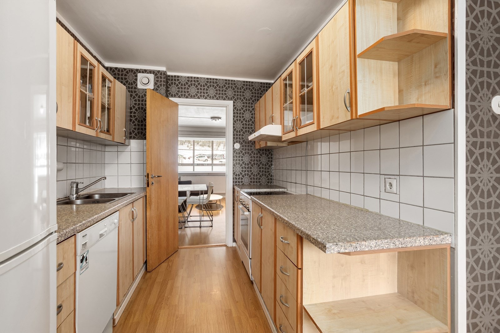 Kjøkken med glatte fronter, benkeplate i laminat og vegg over kjøkkenbenk som er flislagt Galleribilde