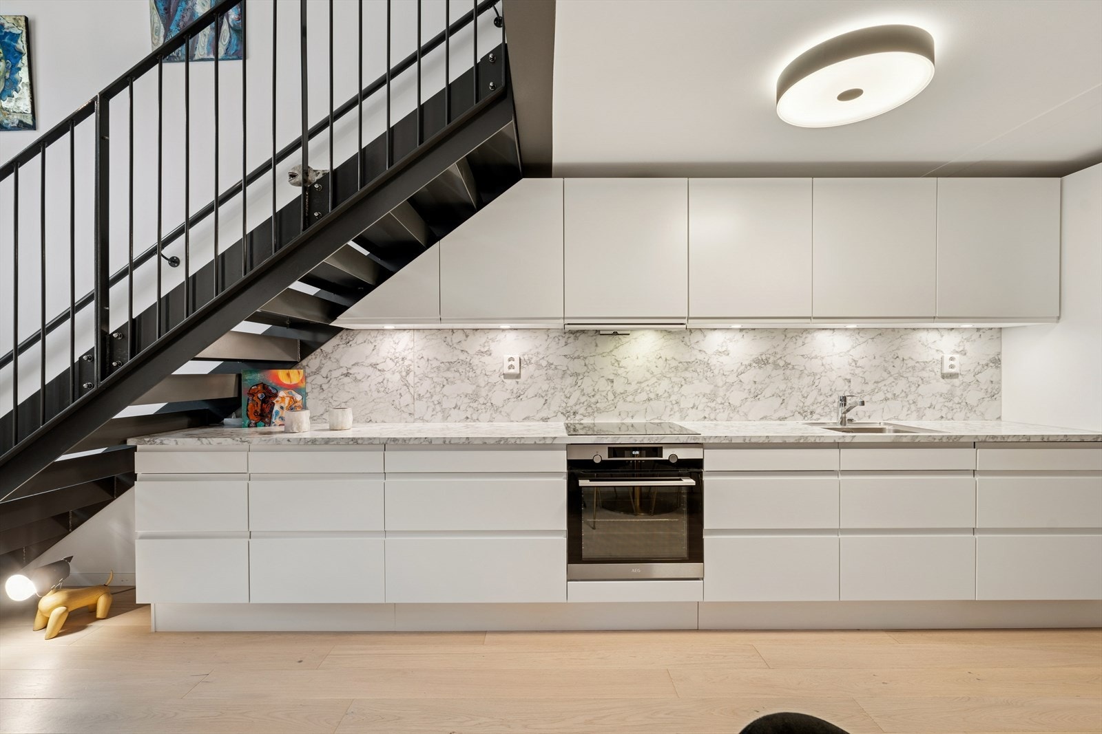 Innredningen består av hvite, slette fronter med skuffer og skap. Kjøkkenet er utstyrt med helintegrerte hvitevarer bestående av koketopp, stekeovn, kjøl/frys og oppvaskmaskin. Galleribilde