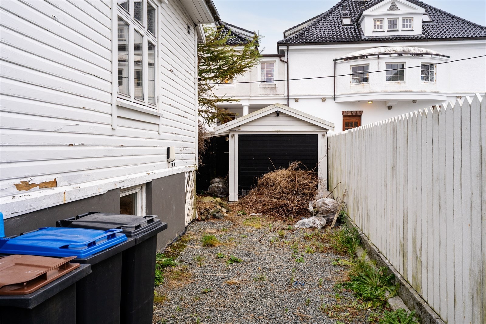 Gårdsrom med parkeringsmulighet. Frittliggende uthus med oppgraderingsbehov. Galleribilde