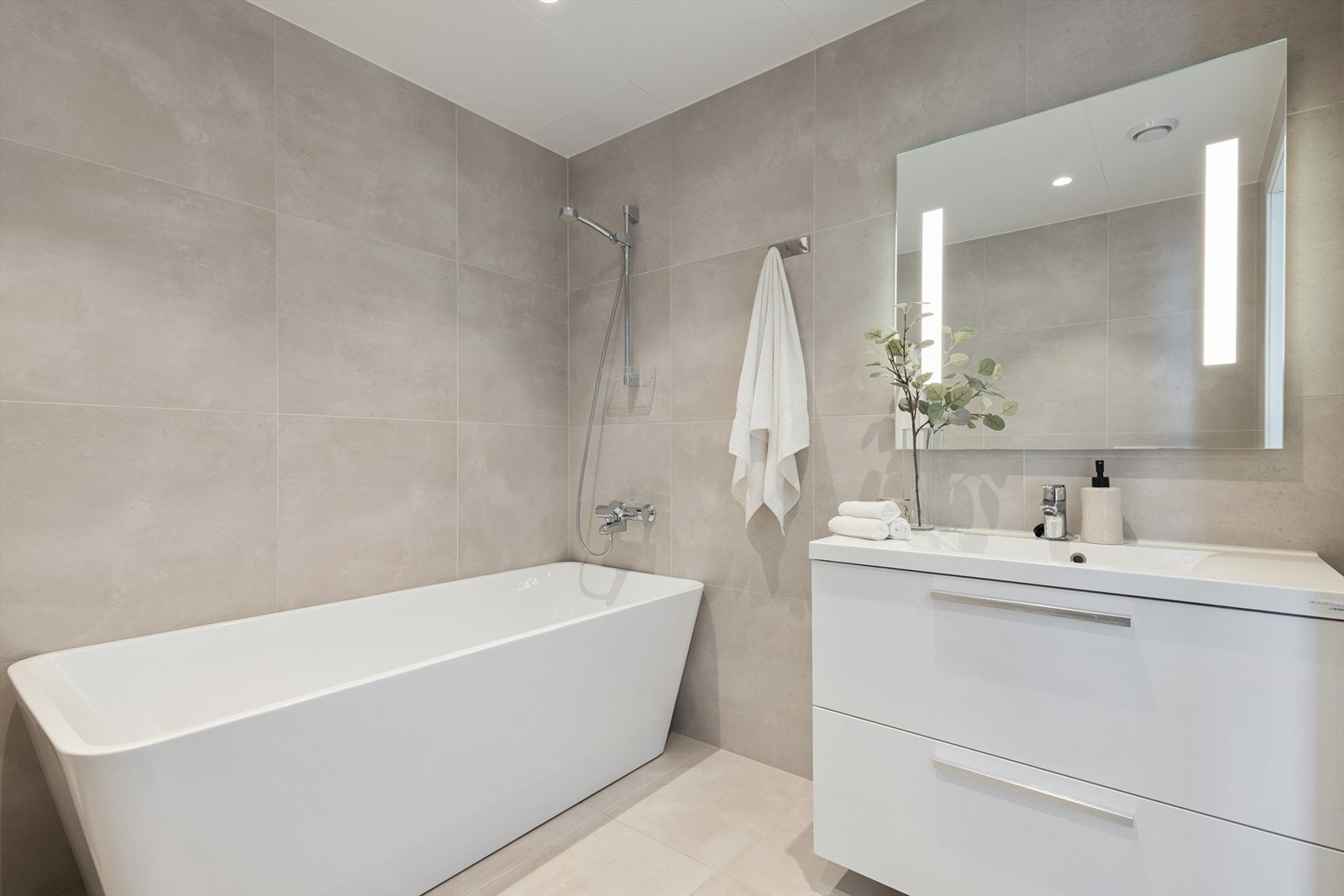 Badet er på 5,3m² og har innredning med nedfelt servant og oppbevaring, høyskap, badekar med dusj og vegghengt toalett. Galleribilde